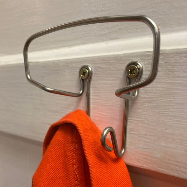 Metal hook on a wooden surface with an orange cloth hanging from it